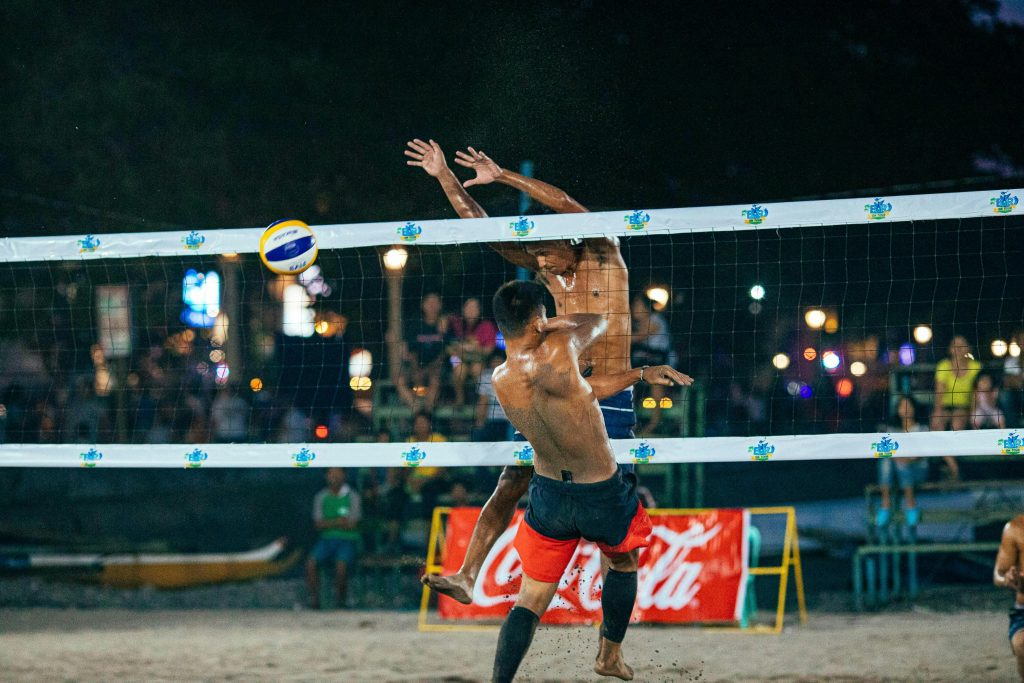 Energetic beach volleyball match under night lights with athletic players.